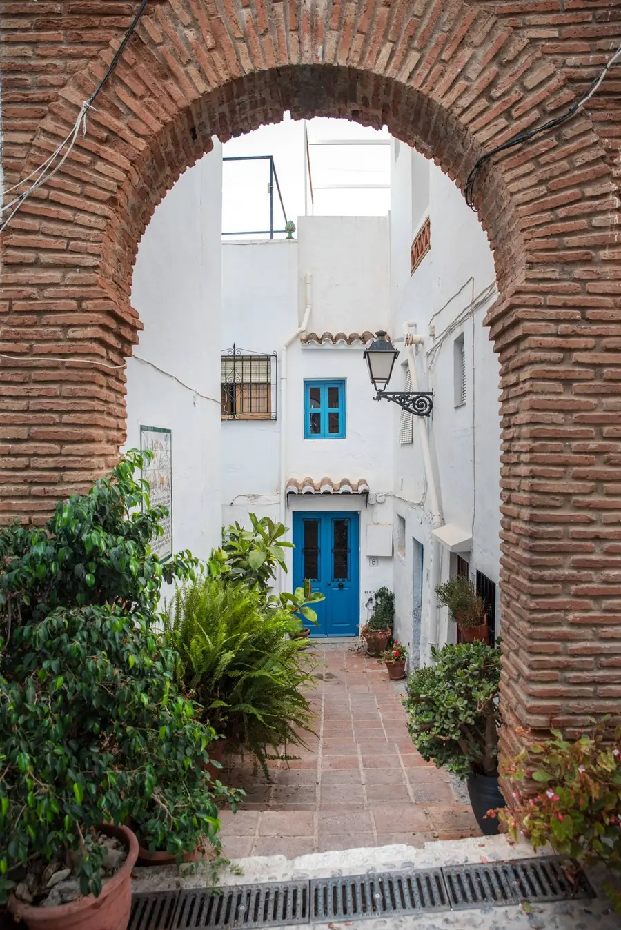 Arco histórico de ladrillo y casas blancas de Frigiliana