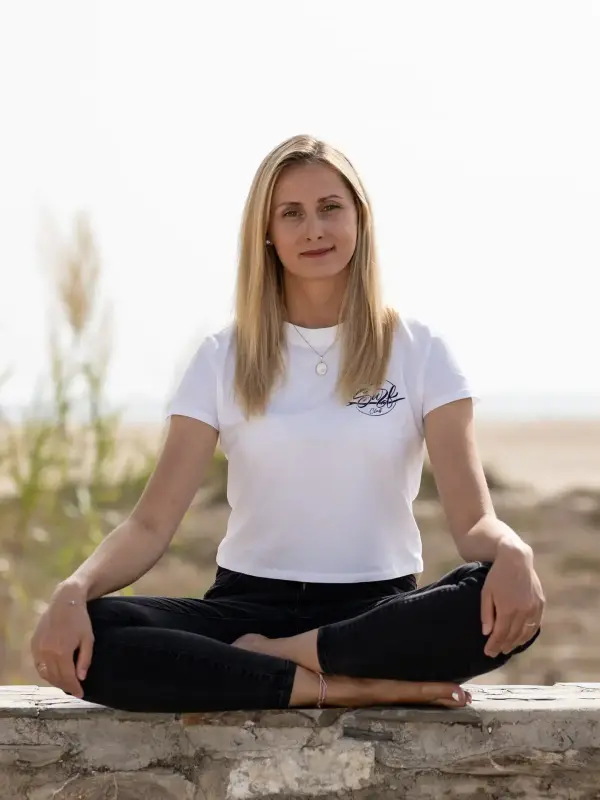 Mona von Work Surf Balance, im Schneidersitz auf einer Strandmauer in Tarifa