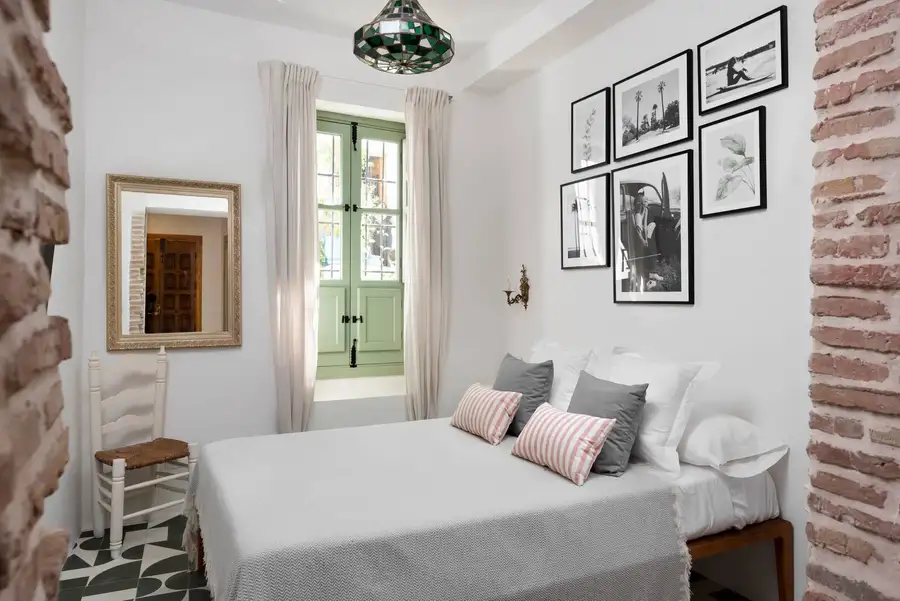 Dormitorio luminoso con ventana de madera verde y arcos de ladrillo en AMARA Farah, Frigiliana