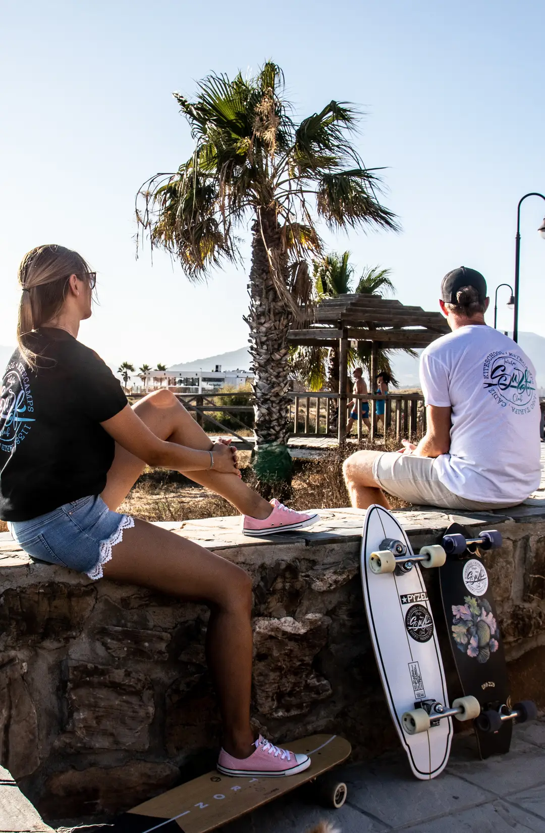 Dos amigos con una tabla bajo una palmera en la playa de Los Lances, Tarifa