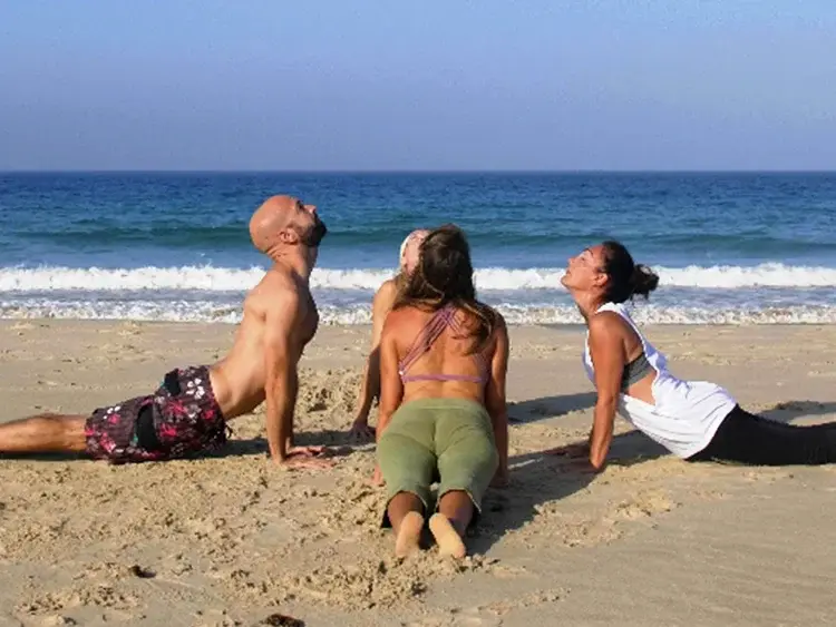 Tres personas en una postura hacia arriba sobre la arena, de cara al mar en una playa de Tarifa