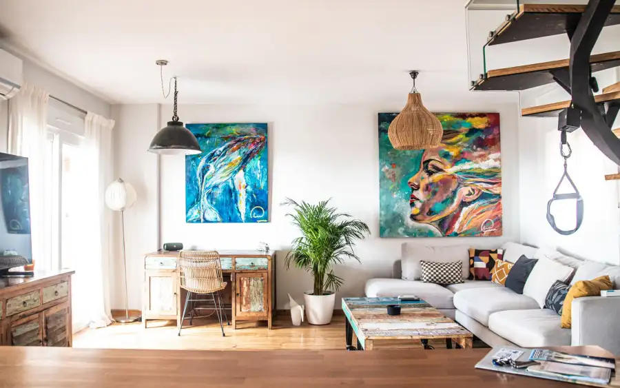 Salón con obras de arte coloridas y escalera abierta en AMARA Family & Surf, Tarifa
