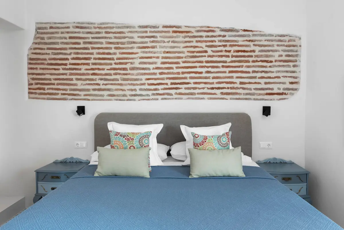 AMARA Zaid: cama doble junto a una pared de ladrillo visto