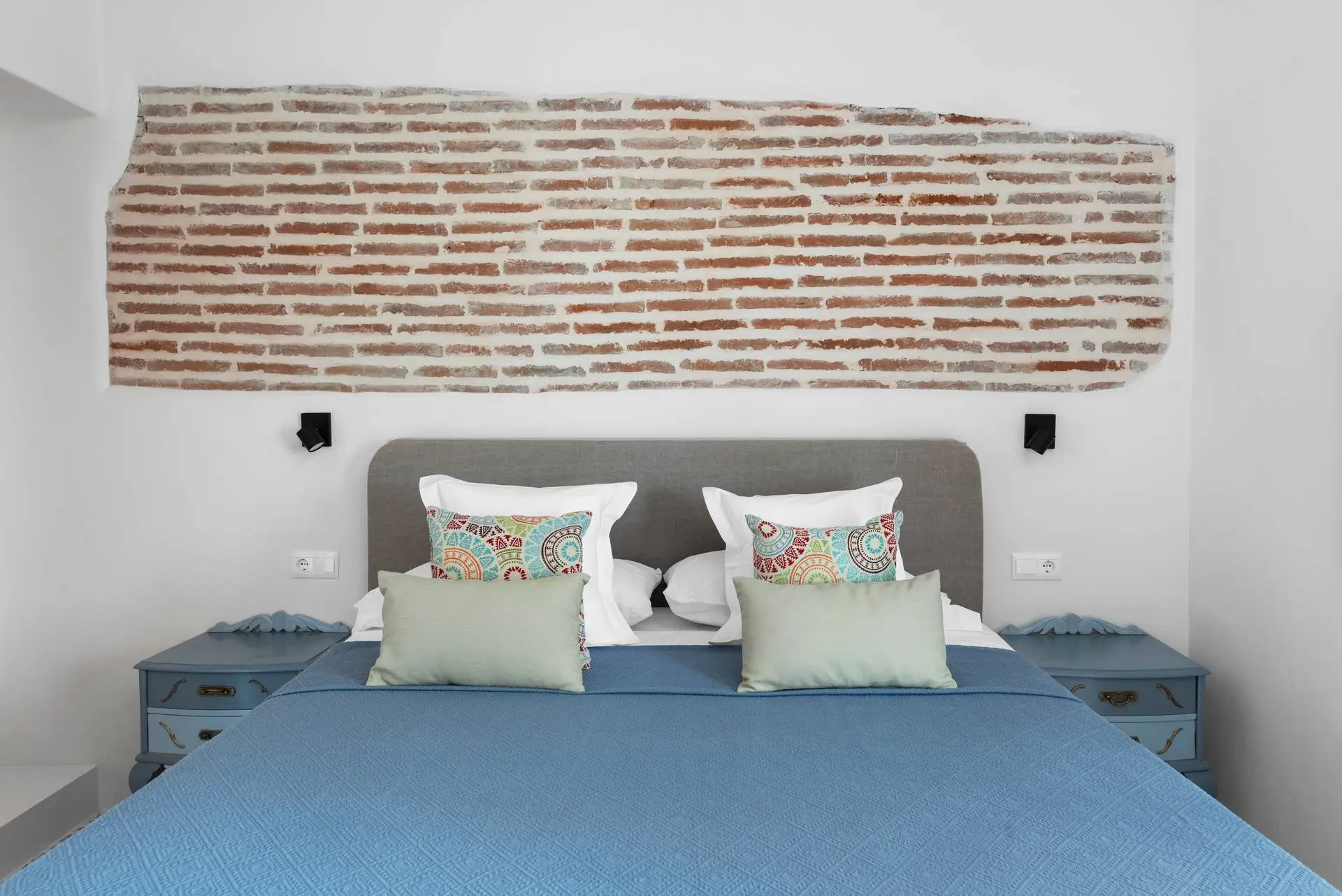 AMARA Zaid: cama doble junto a una pared de ladrillo visto