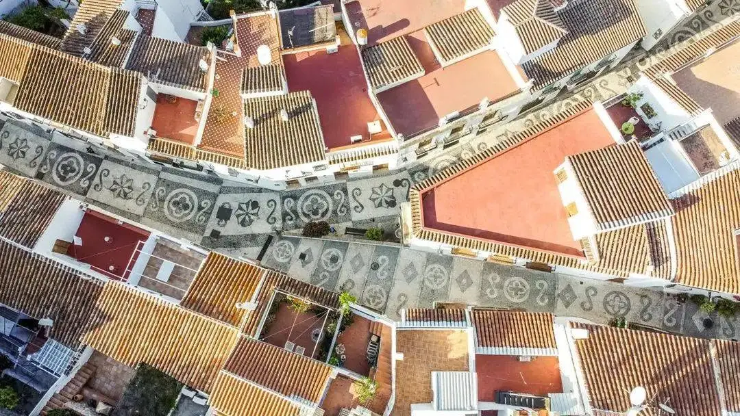 Vista aérea de los tejados de Frigiliana y una calle con mosaico de guijarros