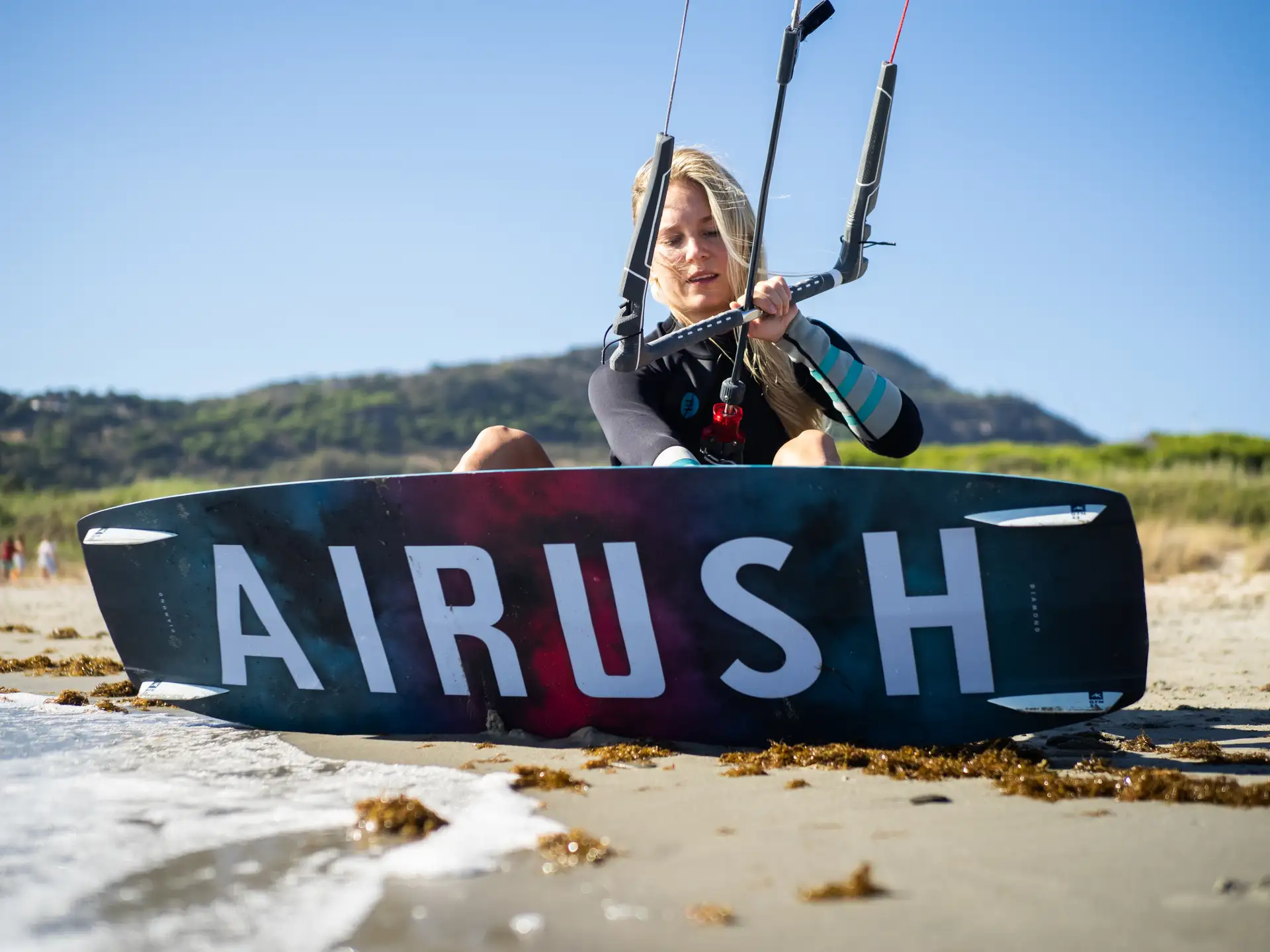 Una principiante en la playa con una tabla twintip de Airush antes de entrar al agua