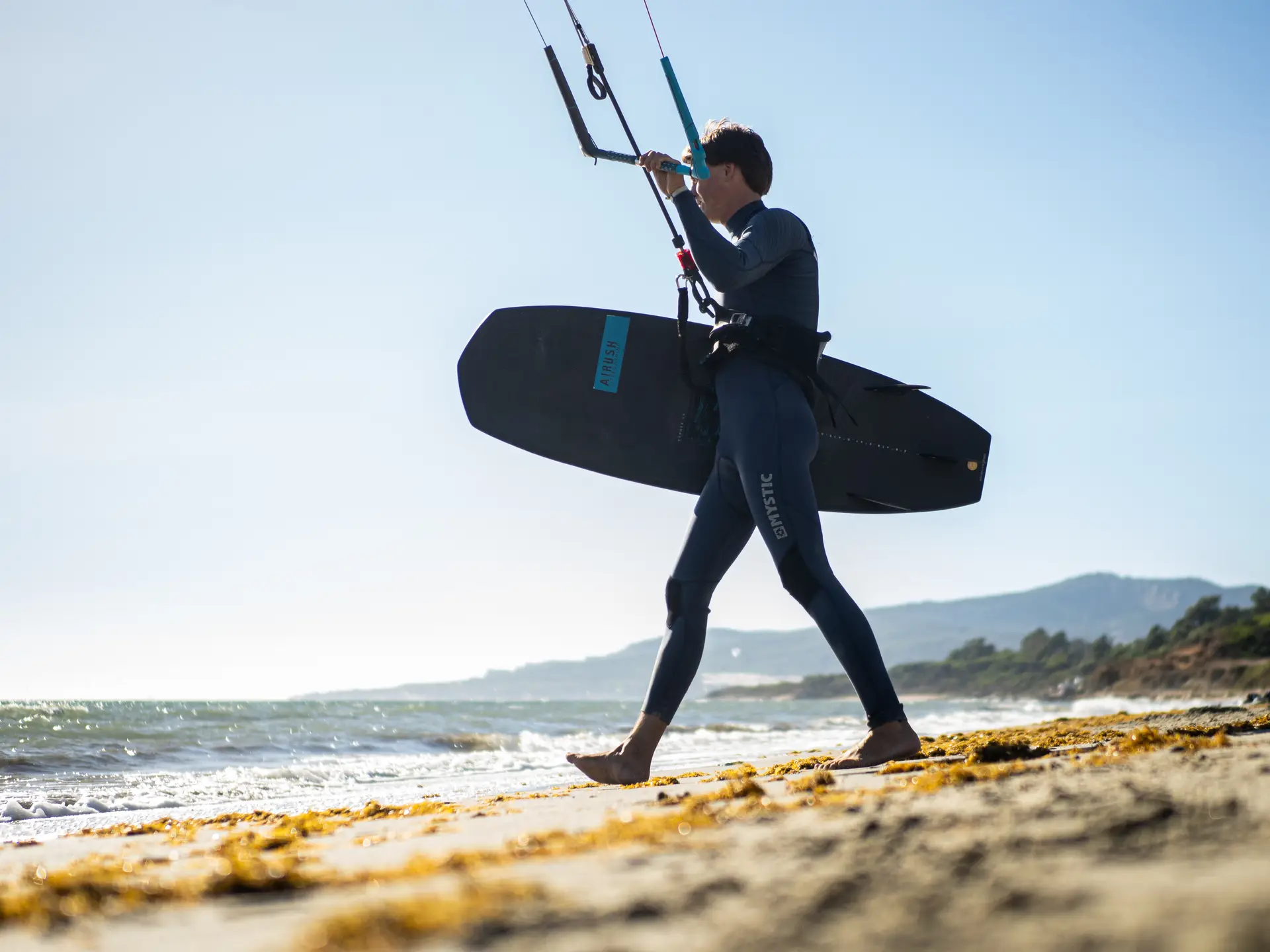 Kitesurfista entrando al agua con la tabla en la playa de Los Lances
