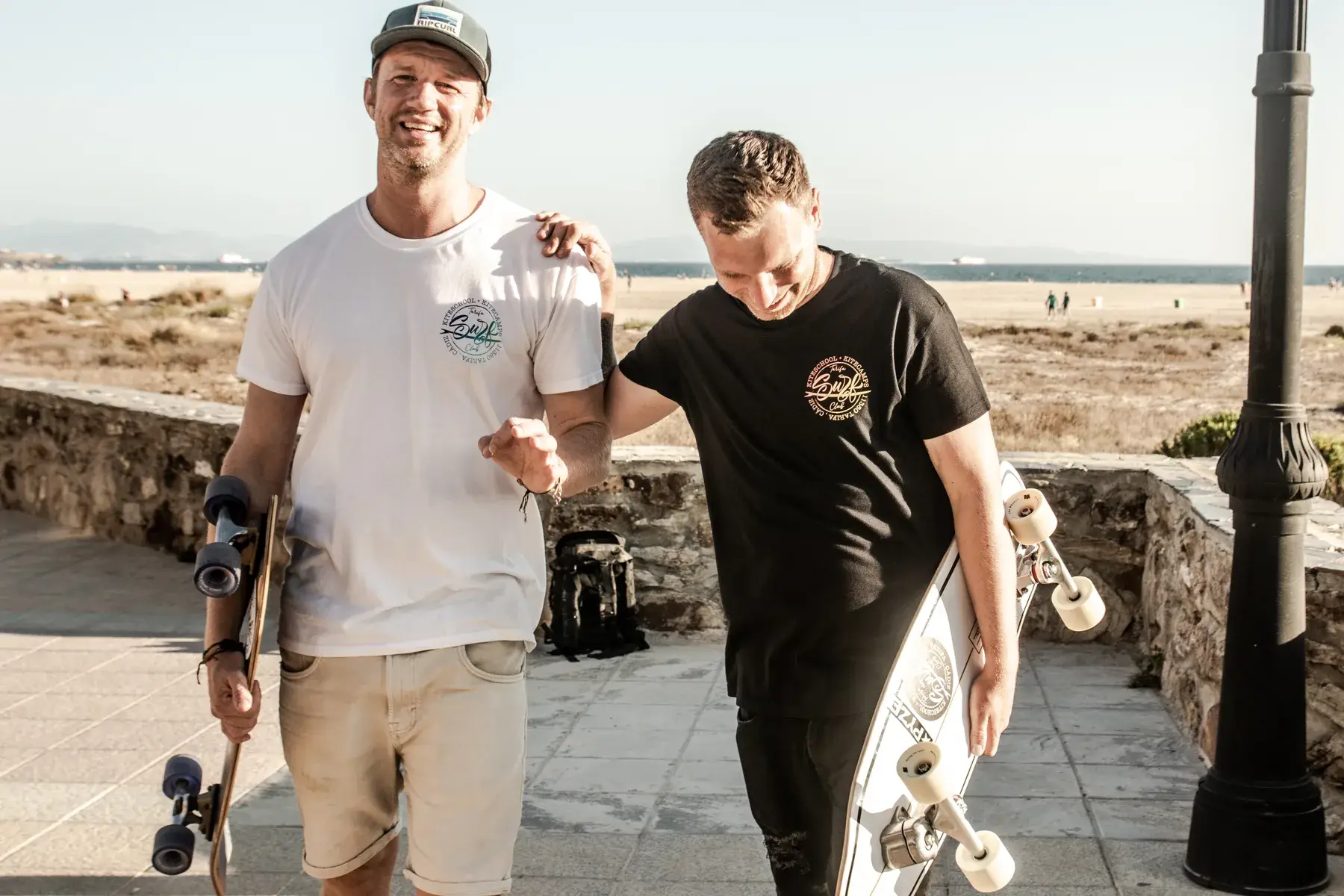 Mark, de Tarifa Surf Club, y Robert, de AMARA, con sus skates en el paseo de Tarifa