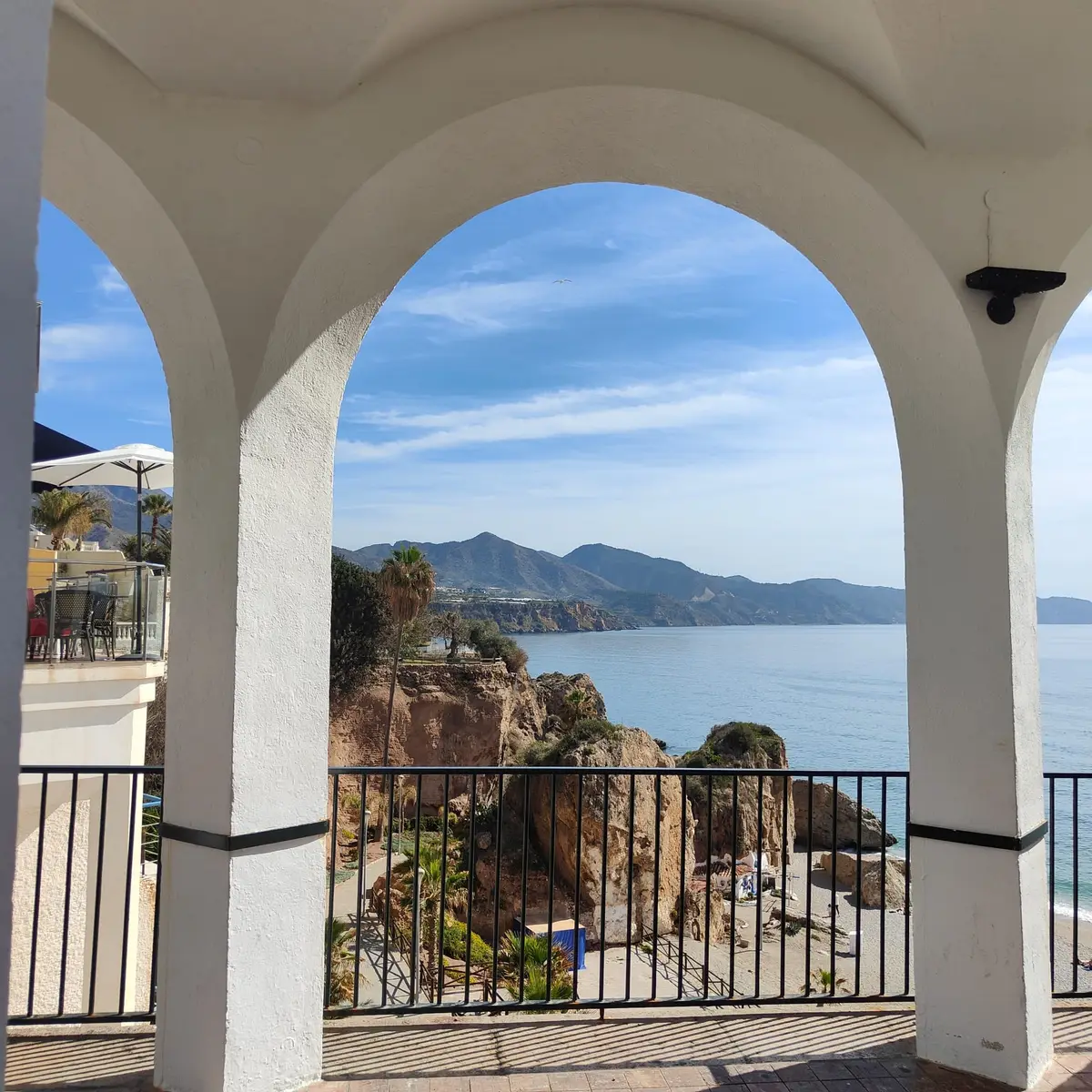 Vista a través de un arco del Balcón de Europa hacia el este por la costa, hasta las montañas