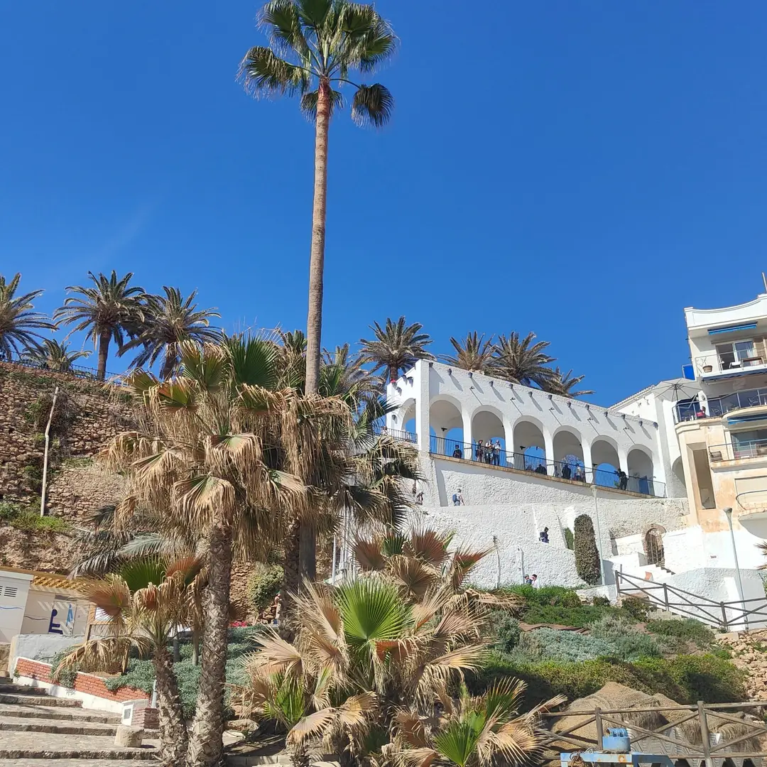 Palmeras bajo la arcada blanca del Balcón de Europa en Nerja