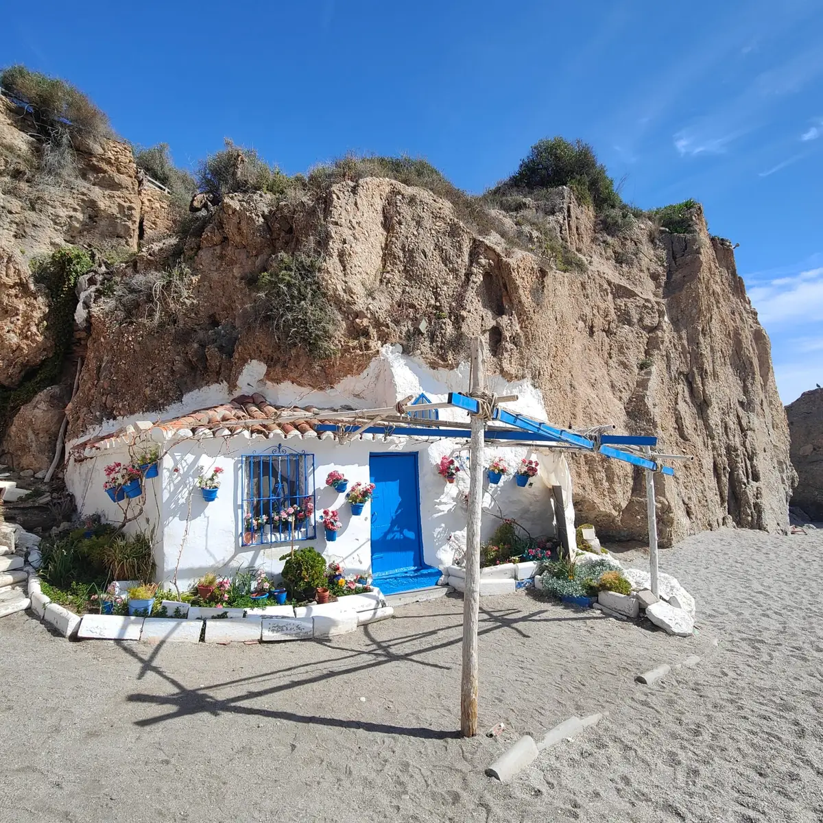 La casita blanca con puerta azul sobre la arena de la playa de Calahonda, bajo los acantilados