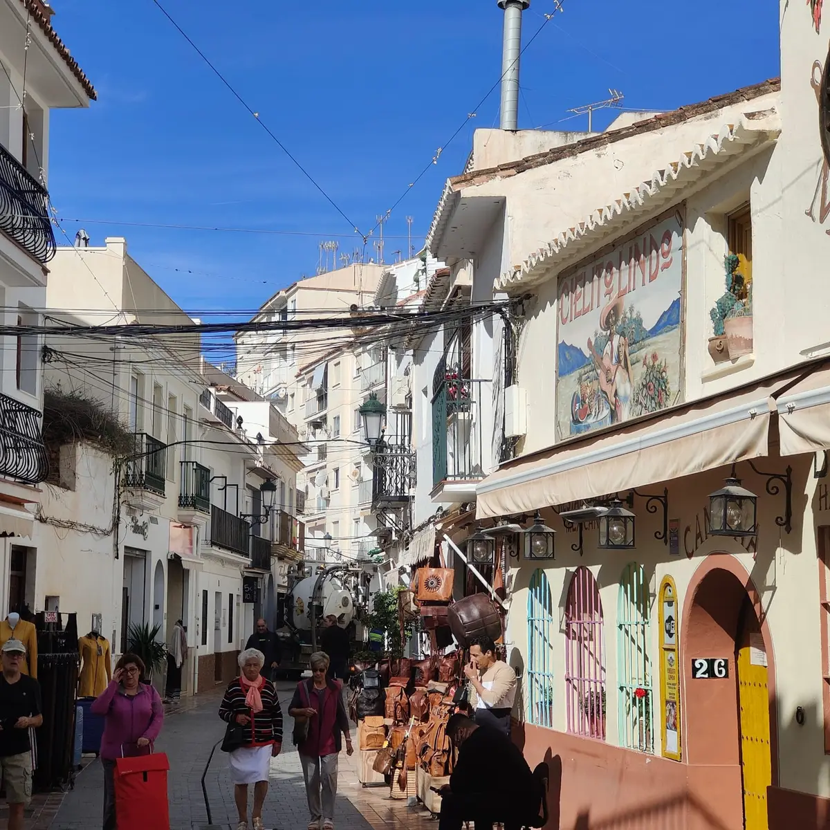 Una calle comercial del centro de Nerja con pequeñas tiendas y gente paseando