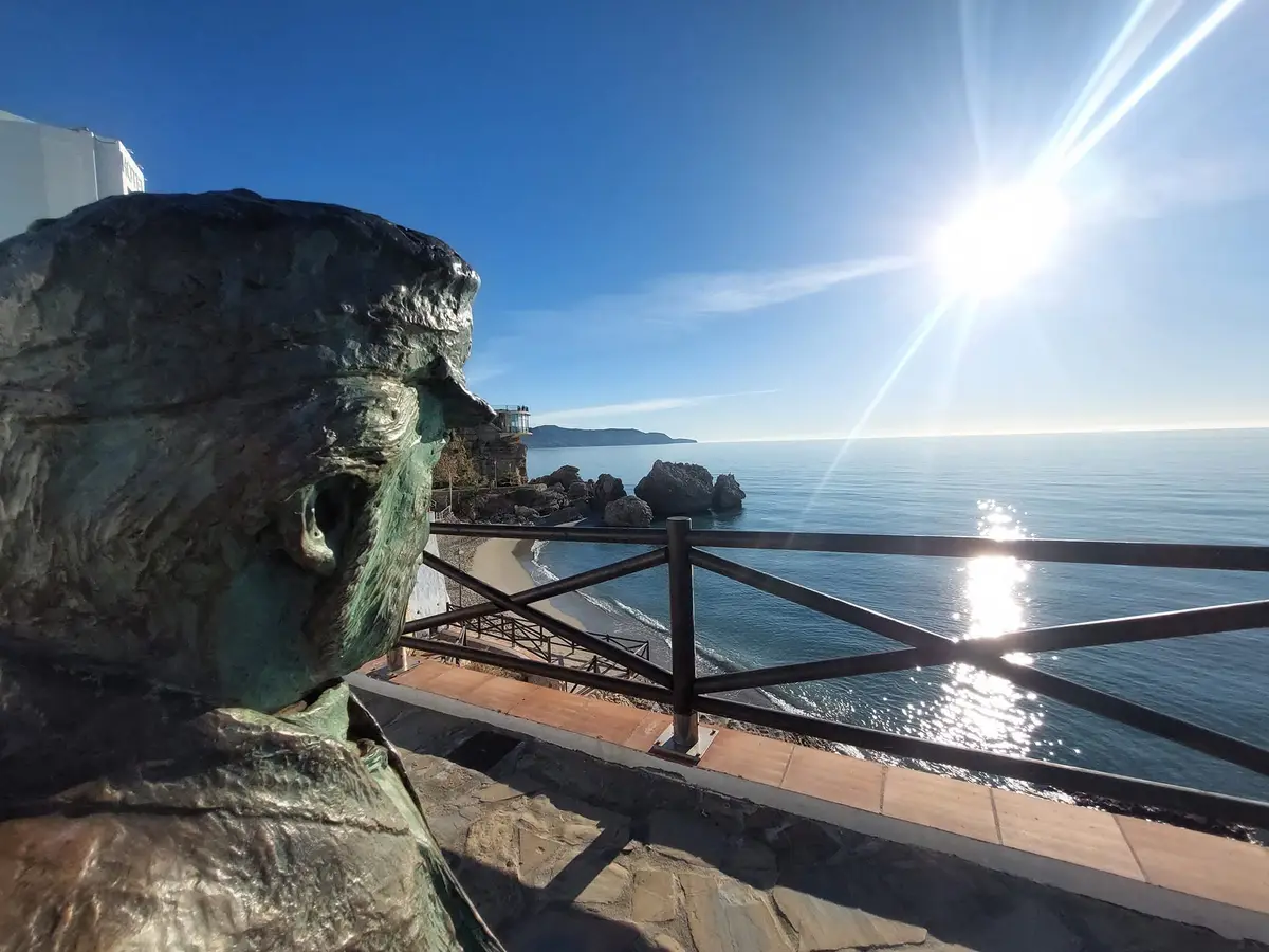 La estatua de bronce del Balcón de Europa a contraluz del sol bajo de invierno sobre un mar en calma