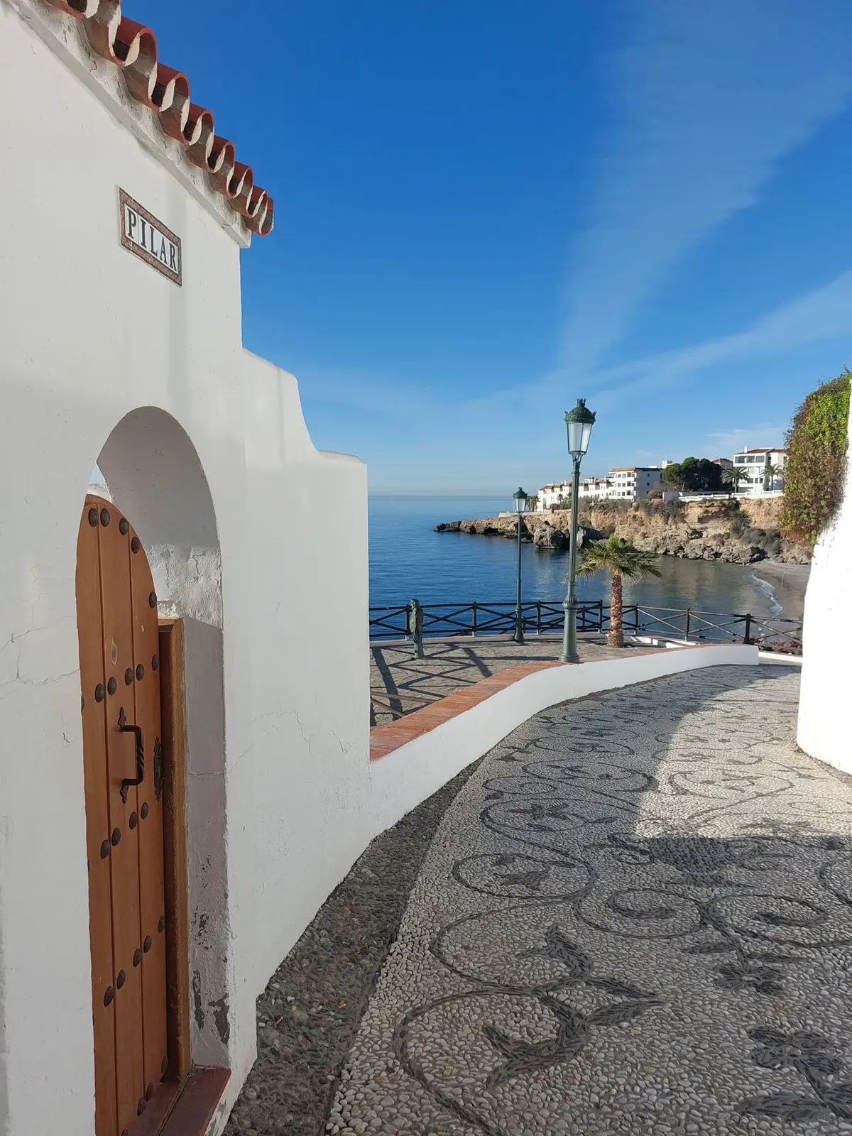 Un pasaje encalado con suelo de mosaico de cantos que baja al mar junto al Balcón de Europa