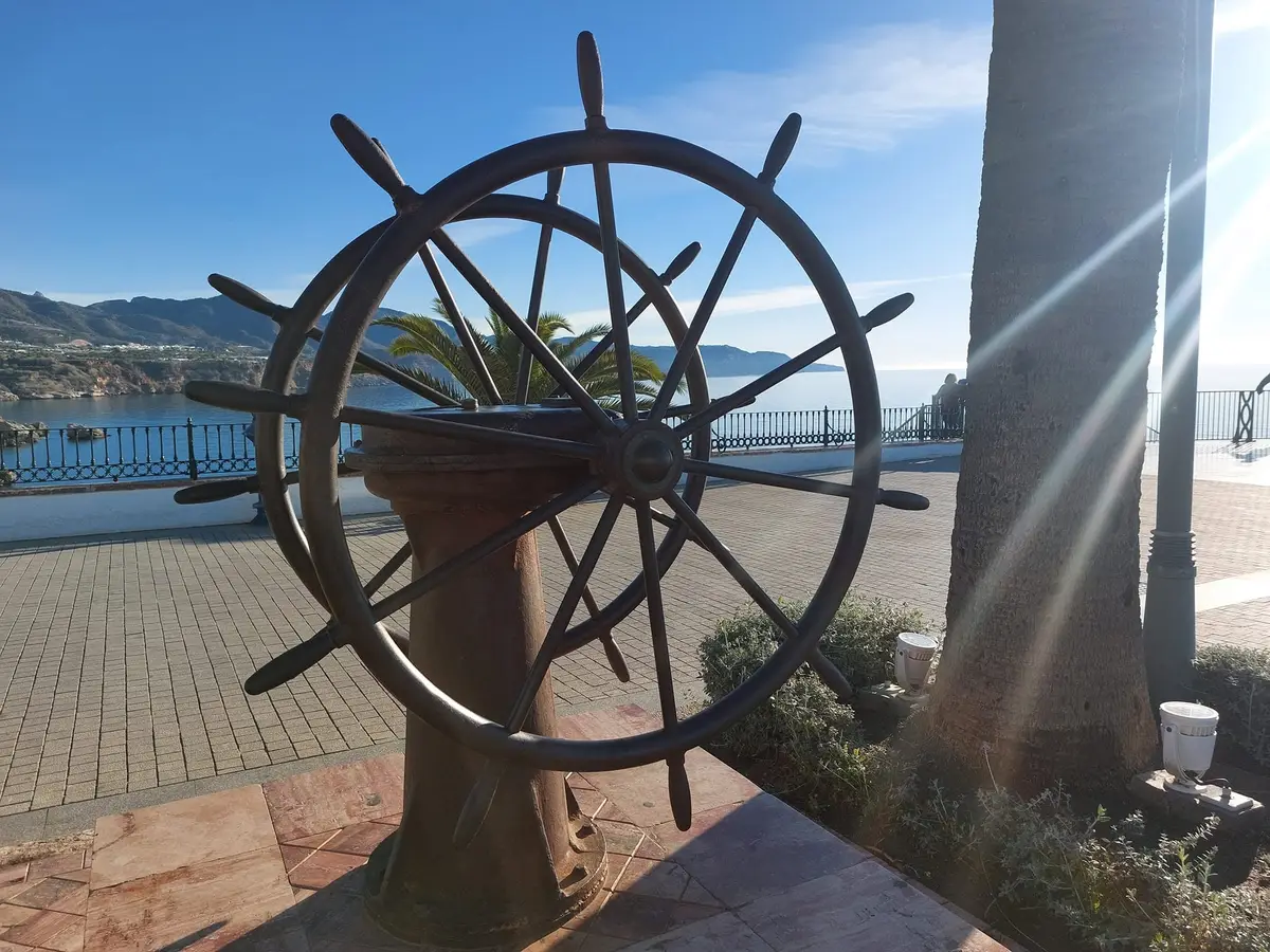 Un timón en el Balcón de Europa, con el mar y la costa detrás bajo la luz de invierno