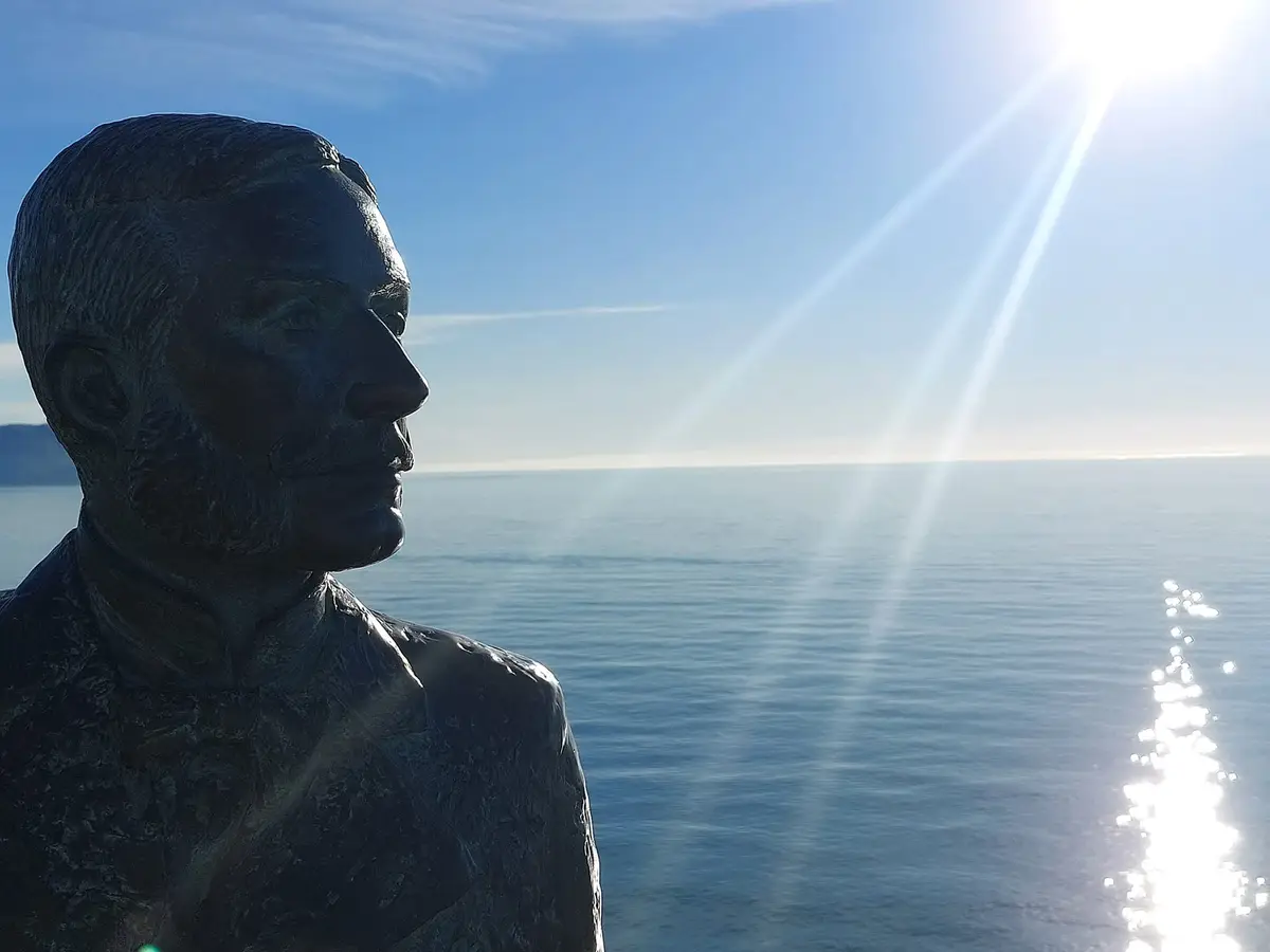 Una estatua del Balcón de Europa a contraluz del sol de invierno sobre el mar