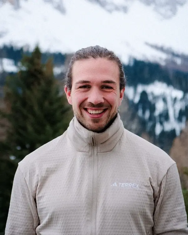 Stefano von Work Surf Balance, in heller Jacke vor verschneiten Bergen