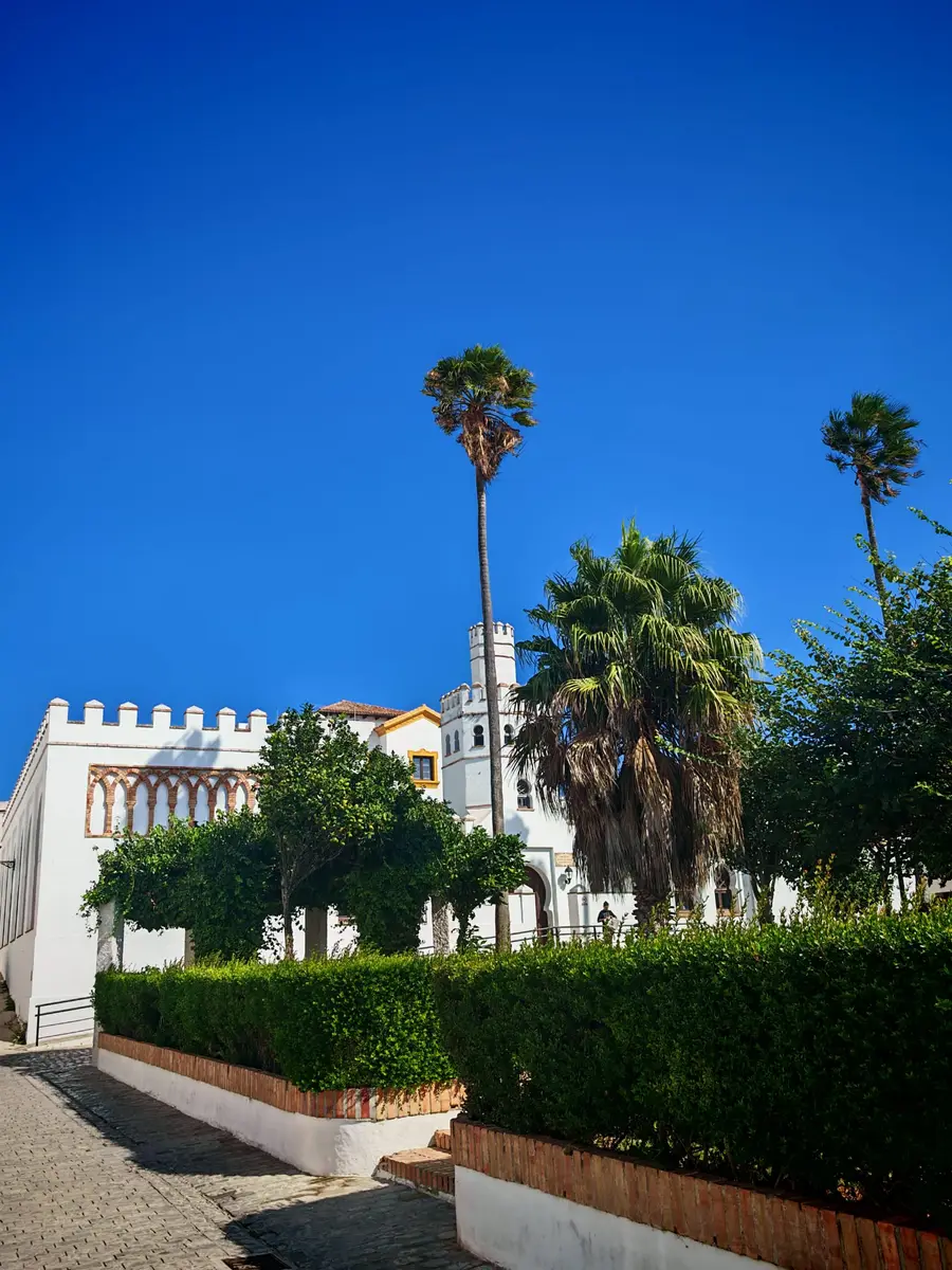 Edificio encalado con almenas y palmeras en una plaza del casco antiguo de Tarifa